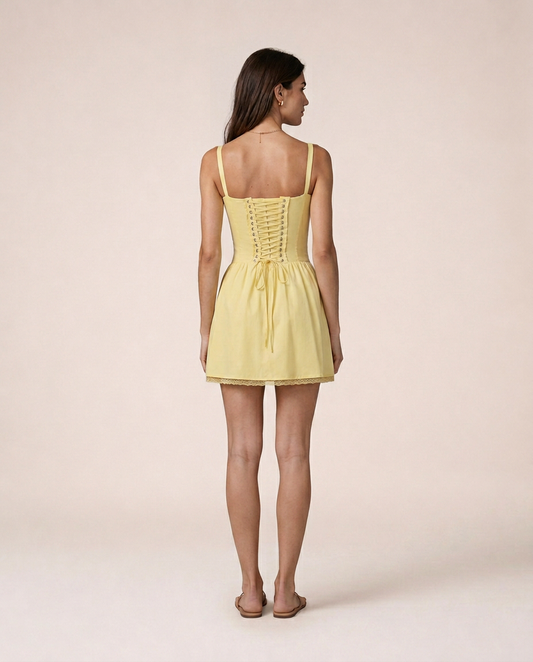 Limone Mini Dress back view featuring lace-up corset detail, adjustable ribbon closure and softly flared skirt in buttery lemon yellow tone