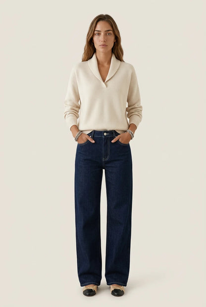 Mujer con el Antonine Jersey beige de Menielle, cuello chal en V y manos en los bolsillos de unos vaqueros oscuros anchos