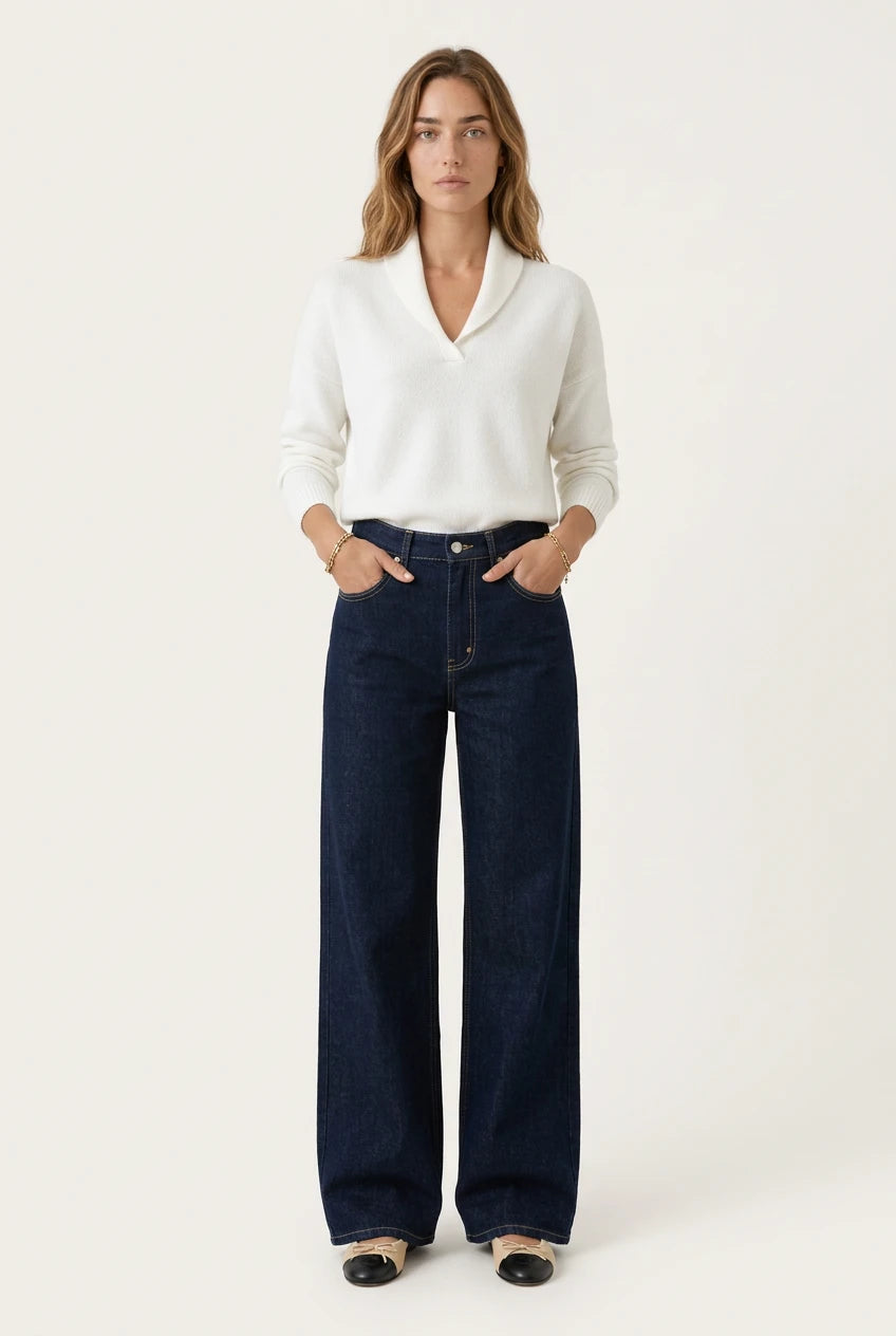Woman wearing the Menielle Antonine Sweater in white, V-shaped shawl collar, hands in the pockets of wide dark jeans