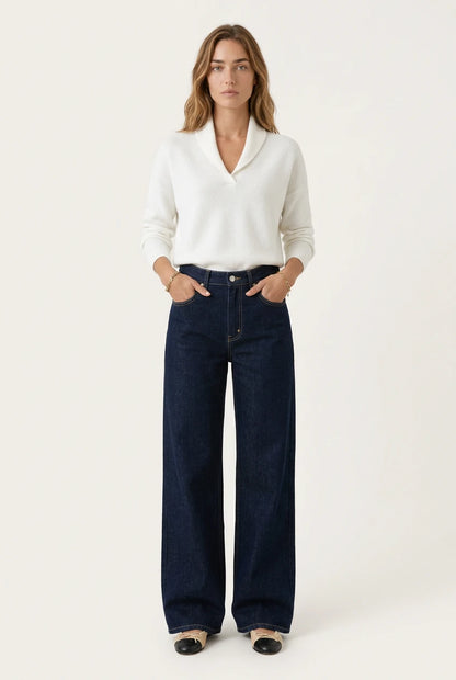 Woman wearing the Menielle Antonine Sweater in white, V-shaped shawl collar, hands in the pockets of wide dark jeans