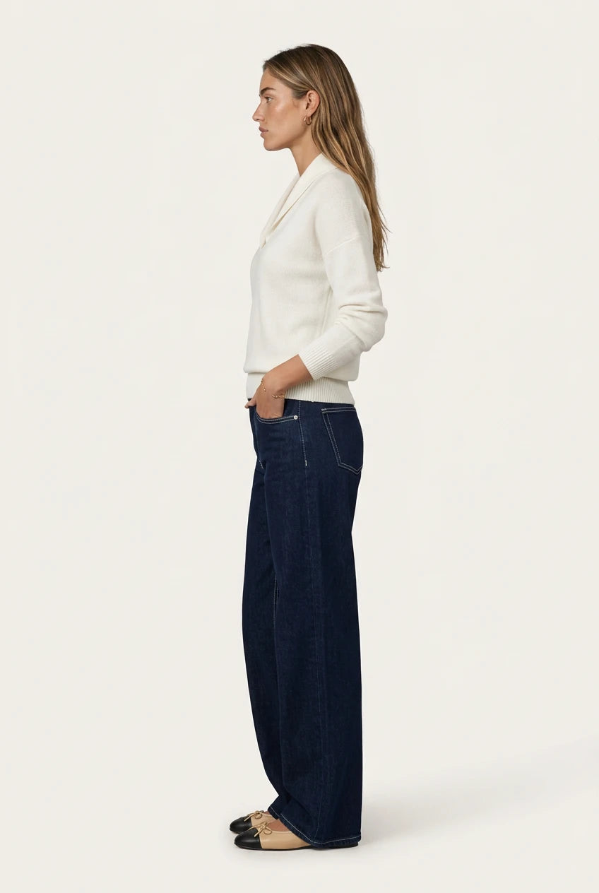 Side view of the Menielle Antonine Sweater in white: knit sweater with a V-shaped shawl collar and ribbed cuffs, with dark jeans